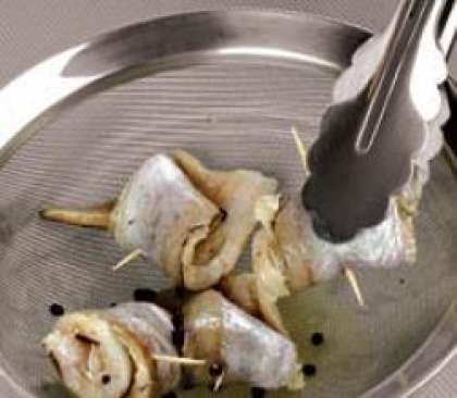 Зеленый лук вымыть, обсушить  бумажными салфетками и мелко  нарезать. Рыбу вынуть из маринада,  переложить на сито. Поставить на миску  или кастрюлю на 10–15 мин., пока  не стечет вся жидкость. Выложить рыбные рулетики на сервировочное блюдо,  посыпать зеленым луком и полить пивным соусом.