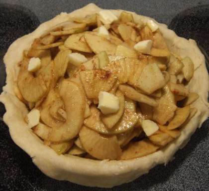 Помещаем яблочную начинку и небольшие кусочки сливочного масла на основу из теста.