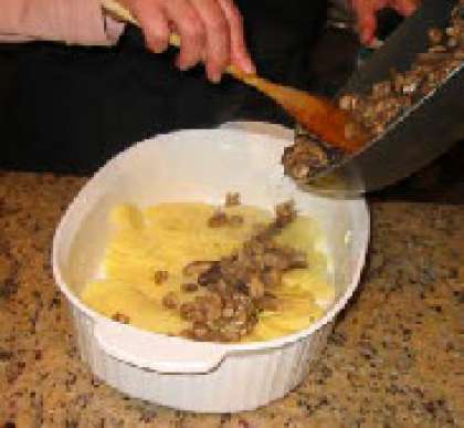 Смажте небольшим количеством сливочного масла форму. Уложите на дно половину количества картофеля, затем ровным слоем грибы.