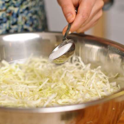 Положите капусту в большую миску и добавить соль.