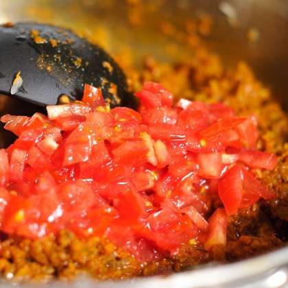Медленно добавить соус из специй к луку, жарьте в течение 5 минут. Положите помидоры в сковороду и обжарьте их вместе с другими ингредиентами. Добавить соль, воду и ранее приготовленный нут-горох.