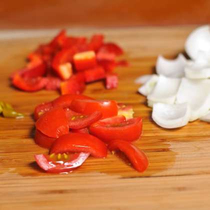 Нарезать 1 помидор, 1 луковицу, перец чили и красный перец на средние кубики.