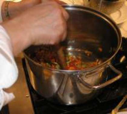 В сотейник влейте 3 ст. л. масла. Включите на средний огонь и нагрейте масло. Добавьте чеснок и обжаривайте в течении нескольких минут. Затем добавьте сельдерей, морковь и томатный соус и немного обжарьте. Постоянно помешивайте.
