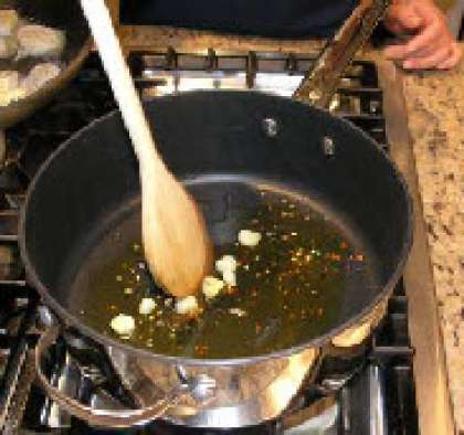 В сотейнике раскалите оливковое масло и быстро обжарьте красный перец и чеснок.
