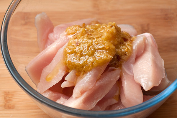 Куриное филе нарежьте поперек волокон полосками толщиной 2 см. Сложите в миску, добавьте маринад.