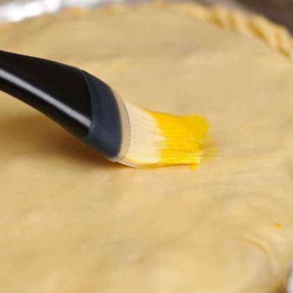 Закрываем начинку второй частью теста, запечатываем края. Смешиваем яйцо с небольшим количеством воды и промазываем кисточкой верхнюю часть пирога. Сделайте небольшие надрезы.