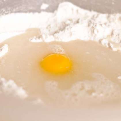 В средней миске смешать вместе сухие ингредиенты для теста. Сделать в середине воронку и залить туда 1 яйцо и теплую воду.