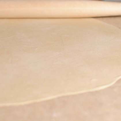 Поделите тесто на 2 части. Присыпьте рабочую поверхность мукой и раскатайте тесто скалкой в тонкие лепешки.