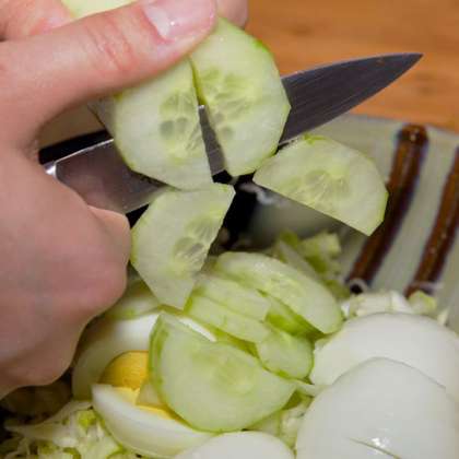 Мелко нарезать капусту, посолить и перемешать. Отварить яйца (вкрутую) и покрошить их в капусту. Очистить огурцы от кожуры и нарезать в салат.
