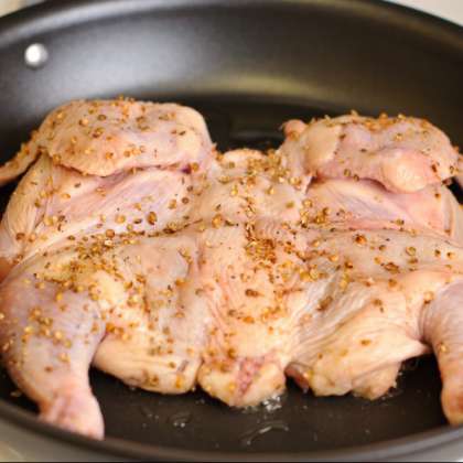 Нагрейте сковороду на среднем огне, добавьте масло. Выложите курицу в сковородку и накройте тарелкой либо крышкой.