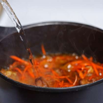 Выложить морковь в чугунок. Добавить остатки соли и тмина. Перемешать и готовить до "размягчения" морковки. Помешивайте каждые 30 сек. Залить 8 чашек кипяченой воды.
