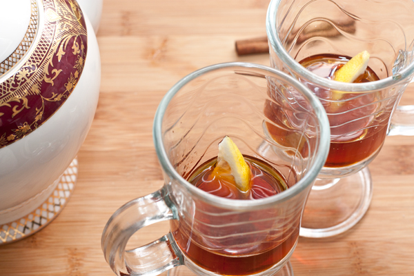 В стаканы для горячих напитков налейте ром или коньяк, положите по дольке лимона и налейте чай.