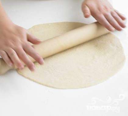 Раскатываем тесто:  Дождитесь пока тесто поднимется. Разделите его на 2 части. Раскатайте скалкой "круги" на присыпанной мукой поверхности. Тесто должно быть очень тонким.