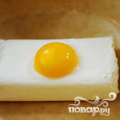 Положить в миску плавленый сыр. Добавить яичный желток.