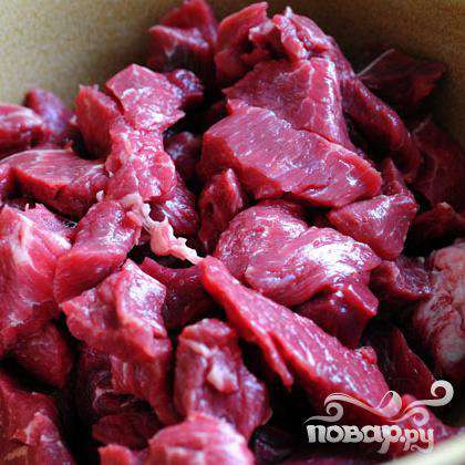 Мясо нарезать средними кубиками и положить в миску.