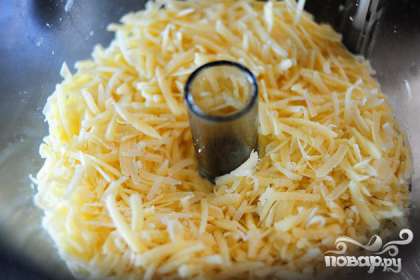 Измельчить сыр с помощью терки или кухонного комбайна.