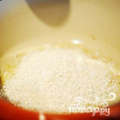Выложить рис Арборио в кастрюлю с луком.