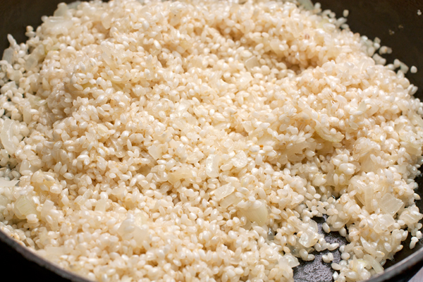 Добавьте рис, не промывая его и готовьте, помешивая, пока зерна не станут полупрозрачными.