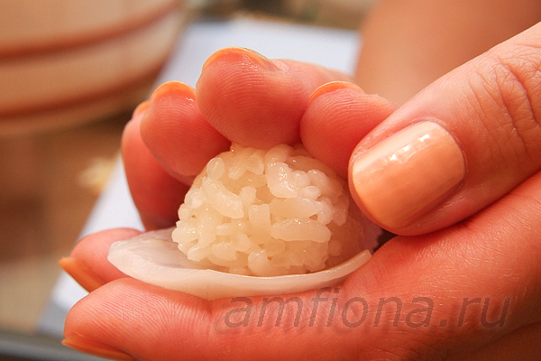 средним и указательным пальцами правой руки слегка спрессуйте рис и кальмара и затем переверните суши рисом вниз.