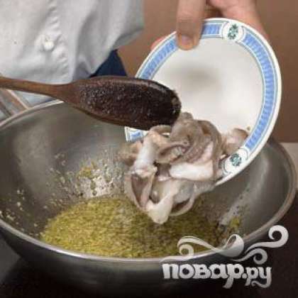 В глубокую сковороду залить масло, обжарить лук с чесноком. Добавить осьминога разрезанного пополам. Продолжать готовить время от времени помешивая.