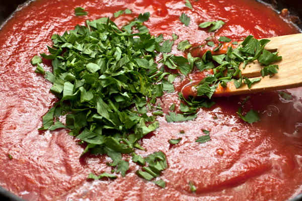 Затем добавьте томатное пюре и измельченные листья петрушки. Если хотите более итальянский акцент, вместо петрушки добавьте базилик.  Доведите соус до кипения и готовьте на небольшом огне, помешивая 3-4 минуты.