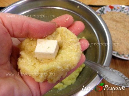 Плавленый сыр режем кубиками – это будет начинка. Кукурузную массу берем небольшими порциями, расплющиваем каждую, кладем в середину кусочек плавленого сыра и формируем котлету-биточек.