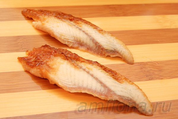 Достаньте угря для суши (unagi kabayaki) из упаковки, разморозьте, снимите шкуру и разрежьте рыбу вдоль на две половины. Держа нож наискосок относительно рыбы и почти параллельно доске, нарежьте угря длинными ломтиками. Половину листа нори разрежьте на тонкие полоски, они пригодятся для того, чтобы закреплять рыбу на рисе.