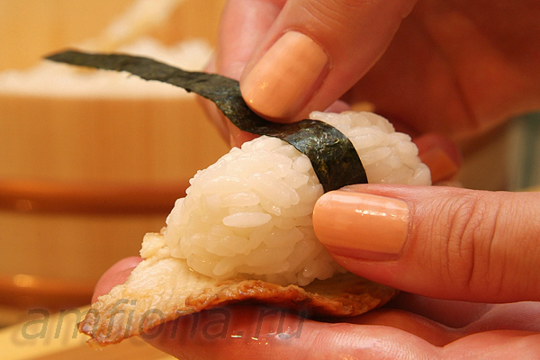 Нигири-суши с угрём обычно оборачивают тонкой полоской из нори, потому что угорь (в отличии от сырой рыбы, например, тунца или лосося) не будет держаться на рисе, когда вы возьмёте суши палочками и окунёте в соевый соус.  