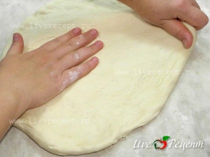 Кладем тесто в миску смазанную маслом, накрываем полотенцем и оставляем в теплом месте подходить на 45-60 мин. Когда тесто подойдет, делим его на две равные части. Если вы любите большую и пышную пиццу, то делить тесто не нужно. Раскатываем тесто для пиццы руками. Для этого выкладываем тесто на присыпанную мукой поверхность и начинаем его растягивать. Прижимаем немного в центре и растягиваем тесто в круг, при этом края теста оставляем чуть толще.