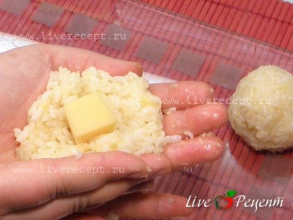 Оставшийся сыр режем на 8 кубиков, рис тоже визуально делим на 8 частей. Берем часть риса, раскладываем на ладошке, в середину кладем кусочек сыра и делаем шарик. Шарик получается размером с крупное куриное яйцо.
