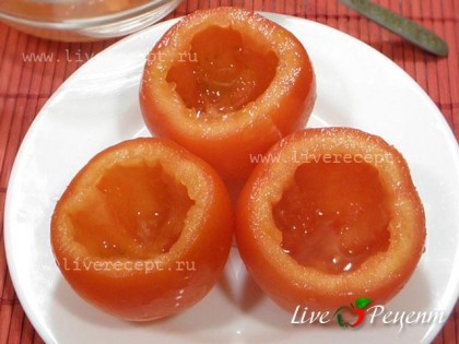 Чтобы приготовить яйца в помидорах по-португальски, отрезаем у помидор шапочку и аккуратно ложкой вычищаем мякоть. Солим и перчим внутри.