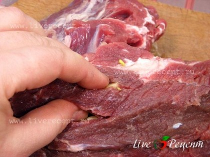 После этого вынимаем мясо, промакиваем его бумажным полотенцем. Теперь острым тонким ножом делаем в мясе надрезы (не слишком частые) и вставляем в них брусочки чеснока.