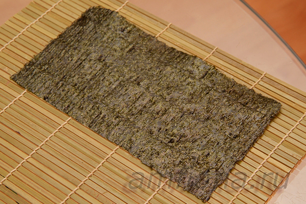 Положите половину листа нори на бамбуковый коврик макису, матовой стороной вверх. 