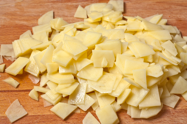Сырой картофель нарежьте очень тонкими ломтиками, чтобы он успел прожариться в процессе приготовления оладий.