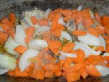 4 Добавить к мясу лук и морковь. Выложить лук и морковь на курицу. Хорошо перемешать и тушить на небольшом огне 5 минут.
