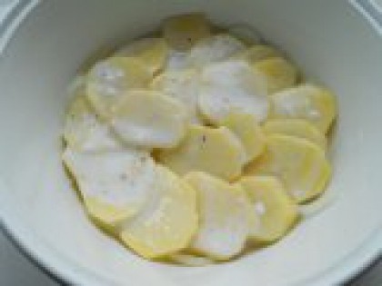 4 Выложить картофель. Вторым слоем, на лук выложить половину очищенного и порезанного тонкими кружочками картофеля. Залить картофель подготовленным сметанным соусом.