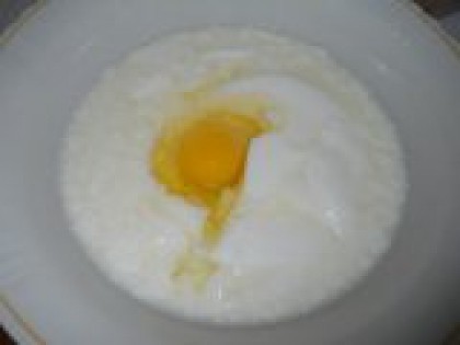 1 В кефир добавить яйцо. Кислое молоко (кисляк) или кефир должно быть теплым. Вылить в глубокую миску, добавить яйцо, щепотку соли и соду.