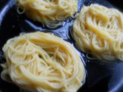 3 Выложить макароны на сковороду. Хорошо перемешать макароны с яйцом. Влить в холодную сковороду немного растительного масла и воды и выложить спагетти в виде "гнезд", формируя небольшое углубление в середине.