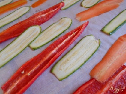Овощи нарезаем на равные полоски при помощи овощерезки. Выкладываем овощи на противень, покрытый пергаментной бумагой и отправляем в духовку на 10-15 минут для запекания.