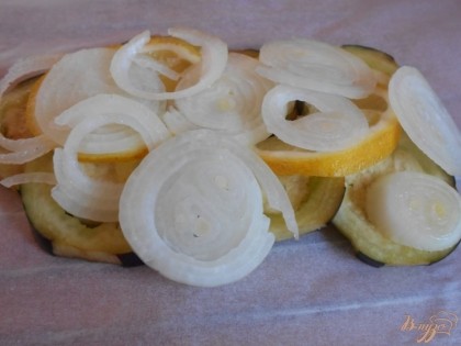 На баклажаны выкладываем нарезанные кружочками лимон и лук.