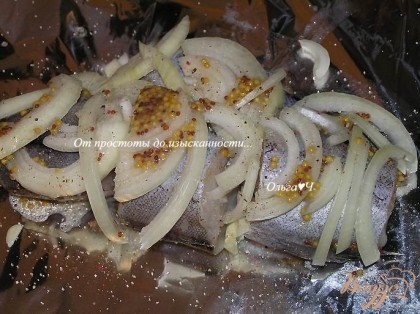 На лист фольги выложить рыбу, посыпать нарезанным кольцами луком, выложить немного горчицы, присолить.