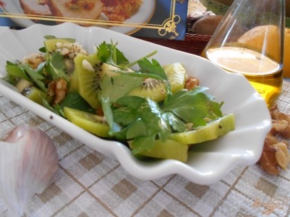Киви добавляем в блюдо к зелени, добавляем мелкопорубленные грецкие орехи и поливаем салат обильно соусом. Хорошо вымешиваем салат.