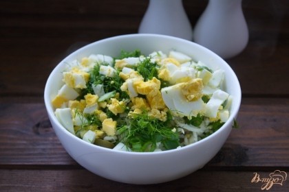 Отварные яйца очистить, нарезать кубиком. Зелень измельчить мелко и добавить в салат.