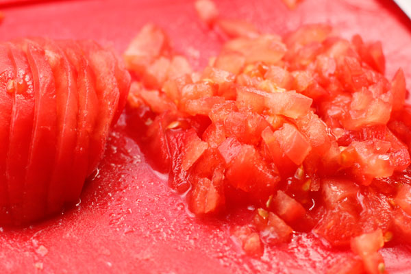 С нижней стороны помидора сделайте неглубокий крестообразный надрез, опустите на минуту в кипяток, а затем снимите кожицу. Нарежьте как можно мельче.