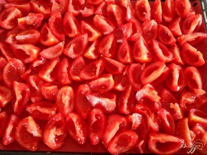 Выкладываем четвертинки помидоров на противень, застеленный бумагой для выпечки.
