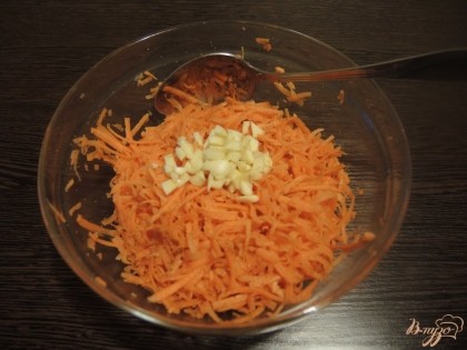 Перемешиваем специи и морковь. Мелко режем чеснок и выкладываем горочкой в миску с морковью.