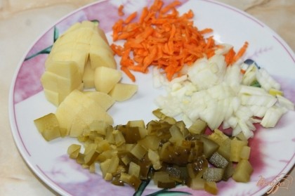 Приступаем к нарезке овощей. Лук репчатый и огурец соленый нарезать мелким кубиком, морковь натереть на крупную терку, картофель нарезать средним кубиком. Добавить картофель к ребрам варить.