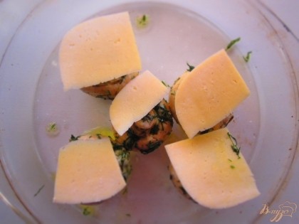 Сыр нарежьте на слайсы и положите на грибы. Поставьте грибы в духовку, выпекайте 15 минут при температуре 200С.