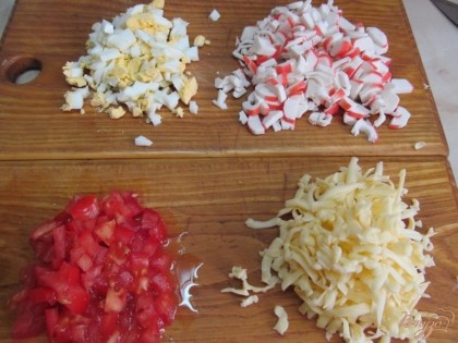 Мелко нарезать яйца, крабовые палочки, помидор, сыр натереть на терке.