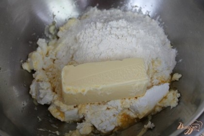 Сливочное масло размягчаем и добавляем в тесто. Муку соединяем с разрыхлителем, насыпаем в миску и замешиваем тесто.